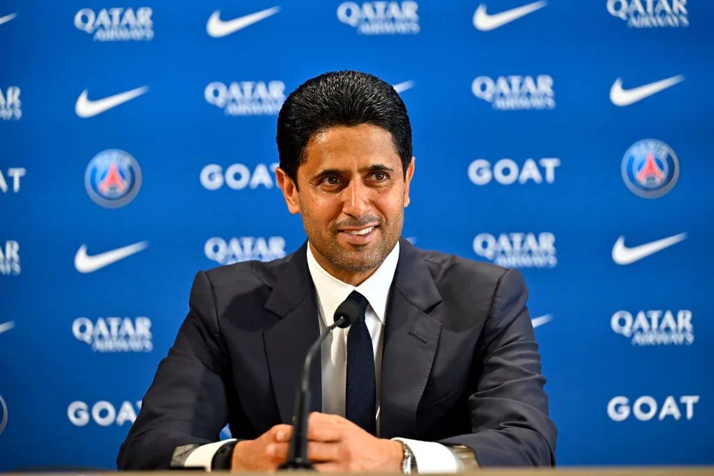 Nasser Al-Khelaïfi, président du Paris Saint-Germain, lors d’une conférence de presse officielle au Camp des Loges, devant un fond bleu aux logos du club et de ses partenaires.